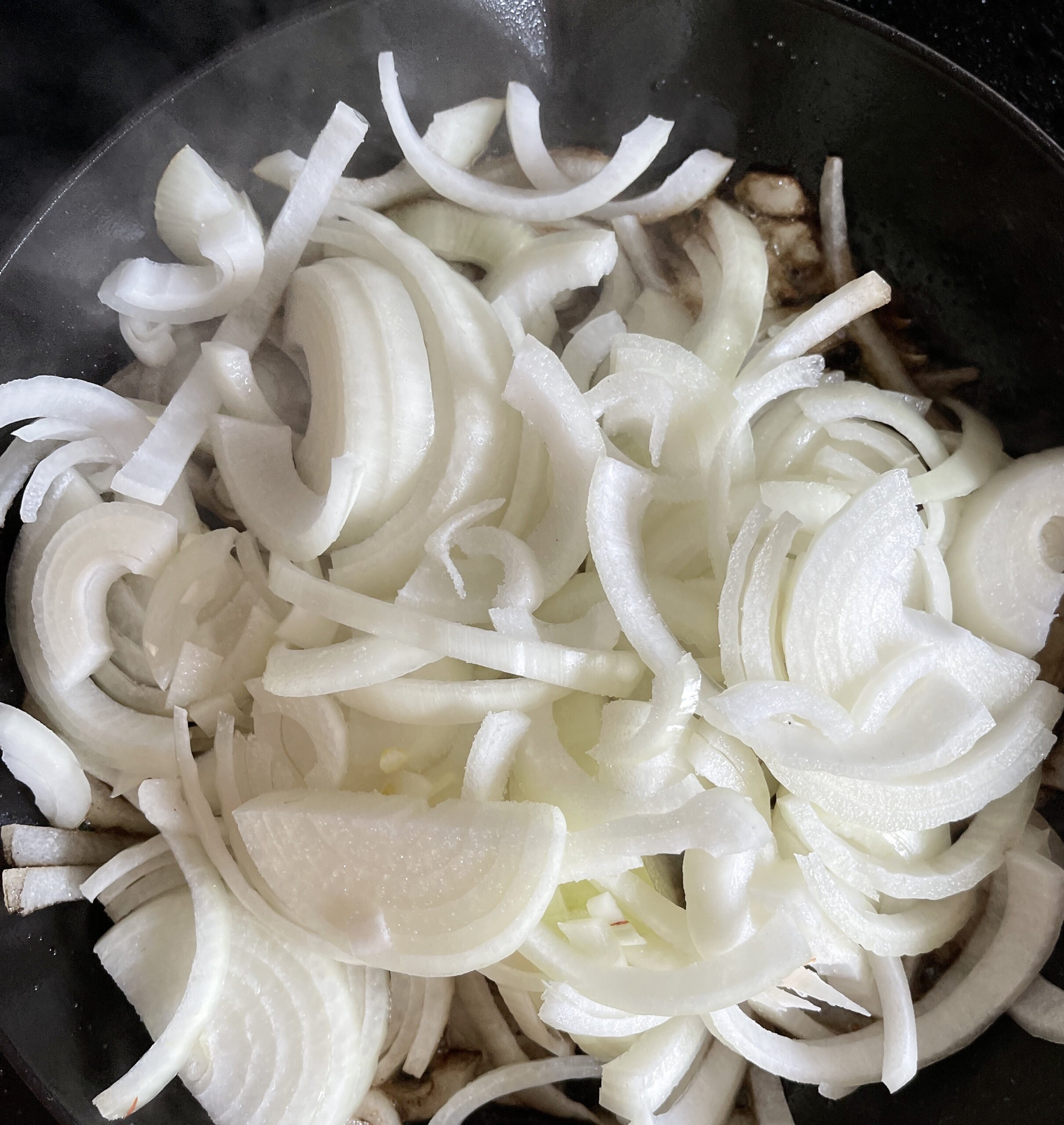 Thinly sliced onions in cast iron pan
